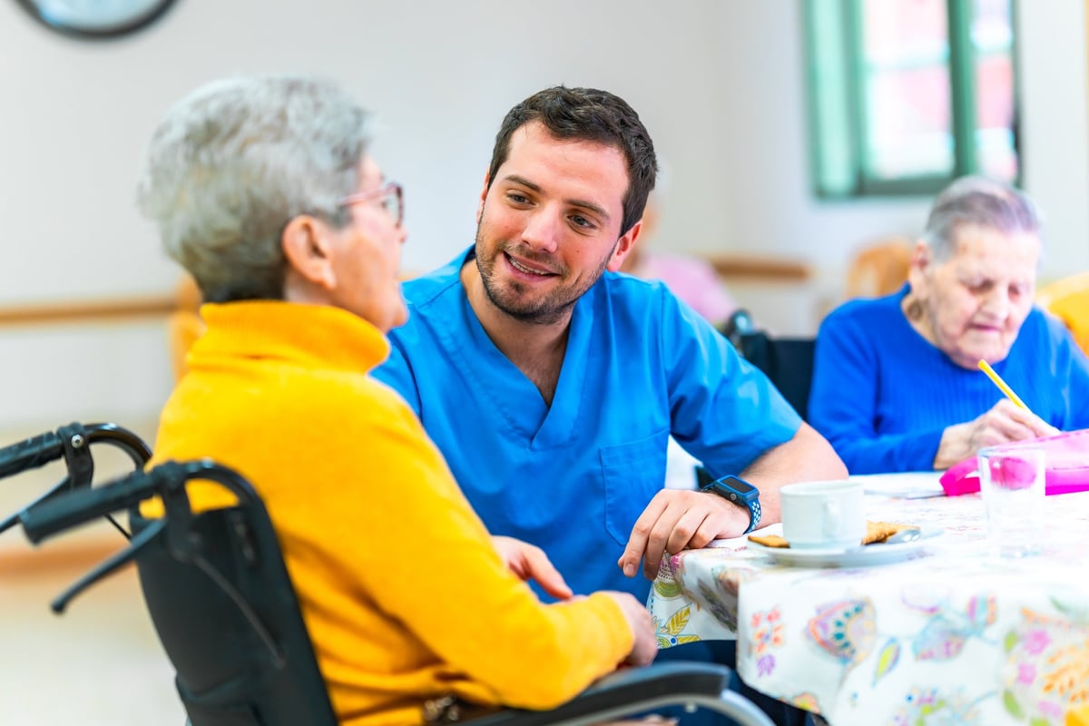 A caregiver talking warmly with an elderly resident in a wheelchair