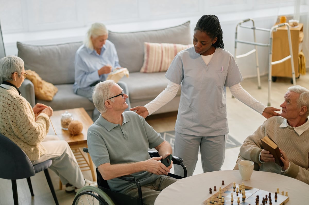 A caregiver sitting with residents around a table during activity time